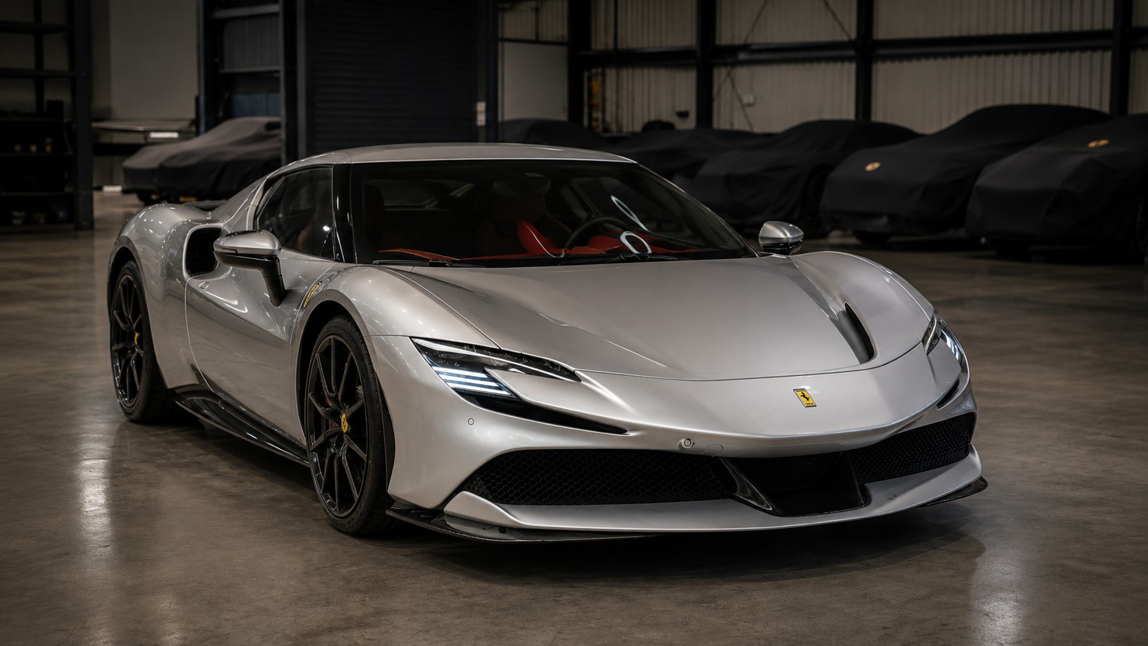 Silver Ferrari SF90 in secure indoor car storage at Equerry 55 in Essex, with covered cars behind it