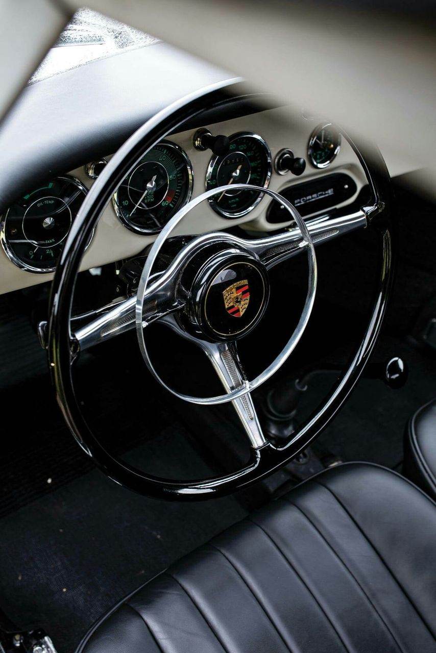 Interior of a classic Porsche 356, showing the steering wheel and dashboard gauges